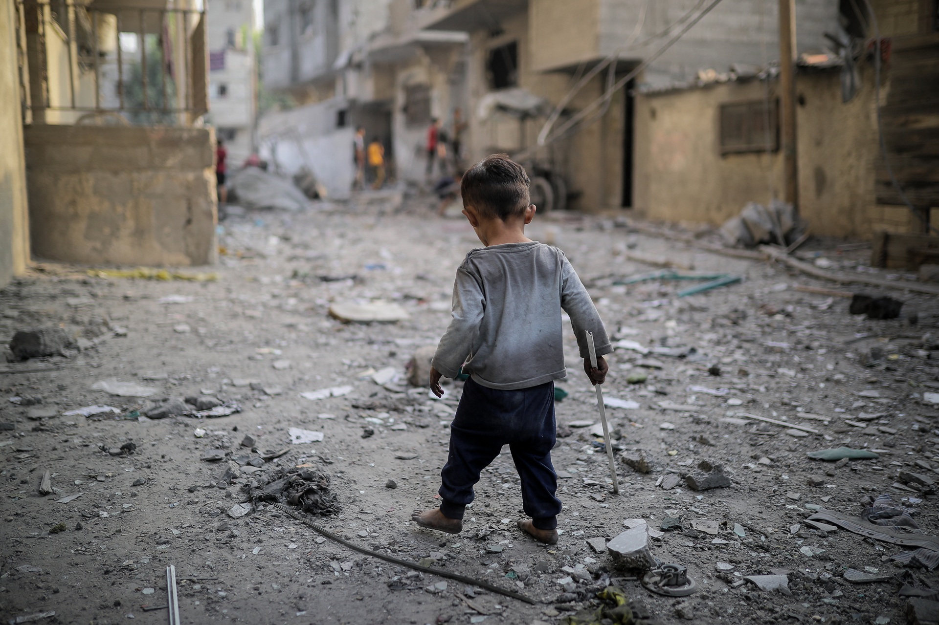 Un garçon court dans une rue en ruines.
