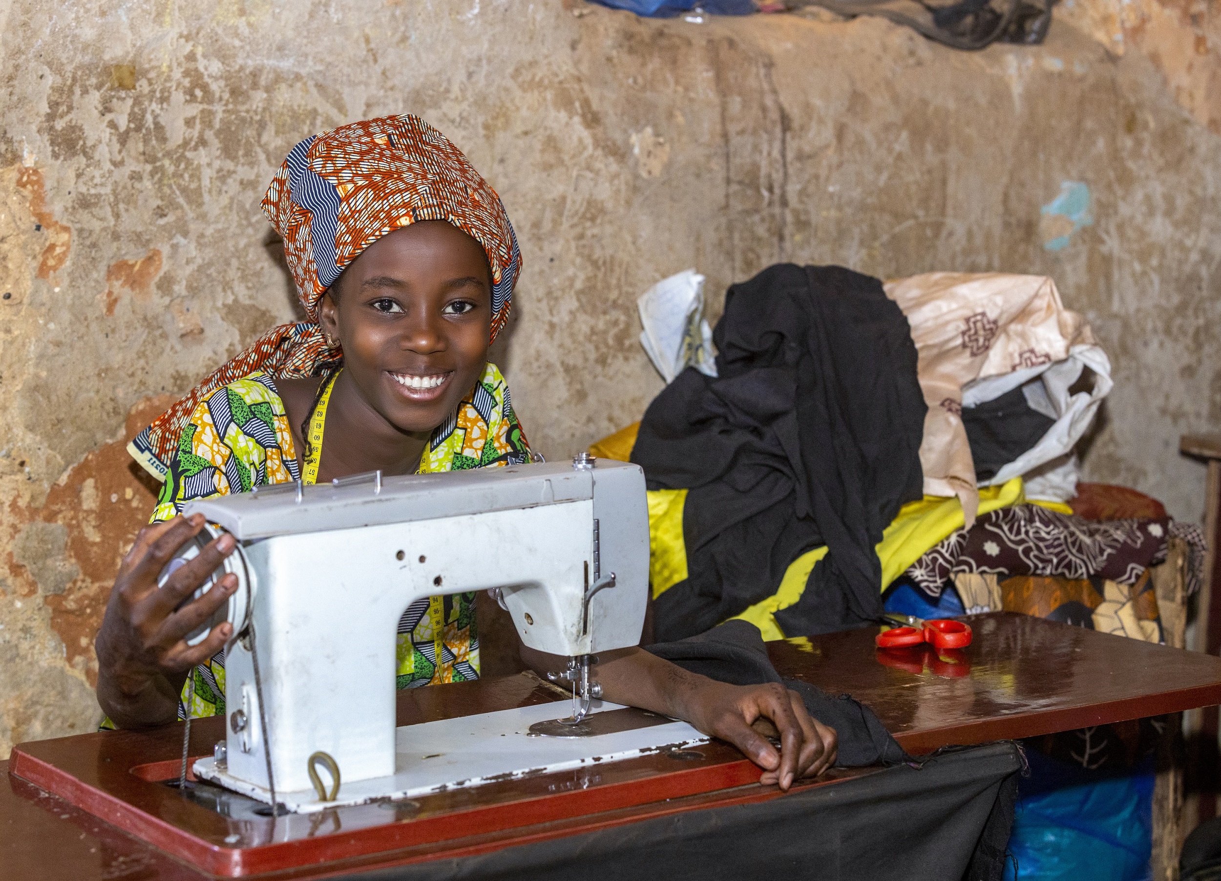 Une jeune est assise devant sa machine à coudre au Niger.