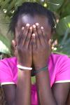 Une jeune fille met ses mains devant son visage.
