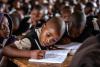 Des enfants sont assis à leur pupitre d'école en train d'écrire.
