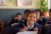Une fillette assise à l'école et souriante.
