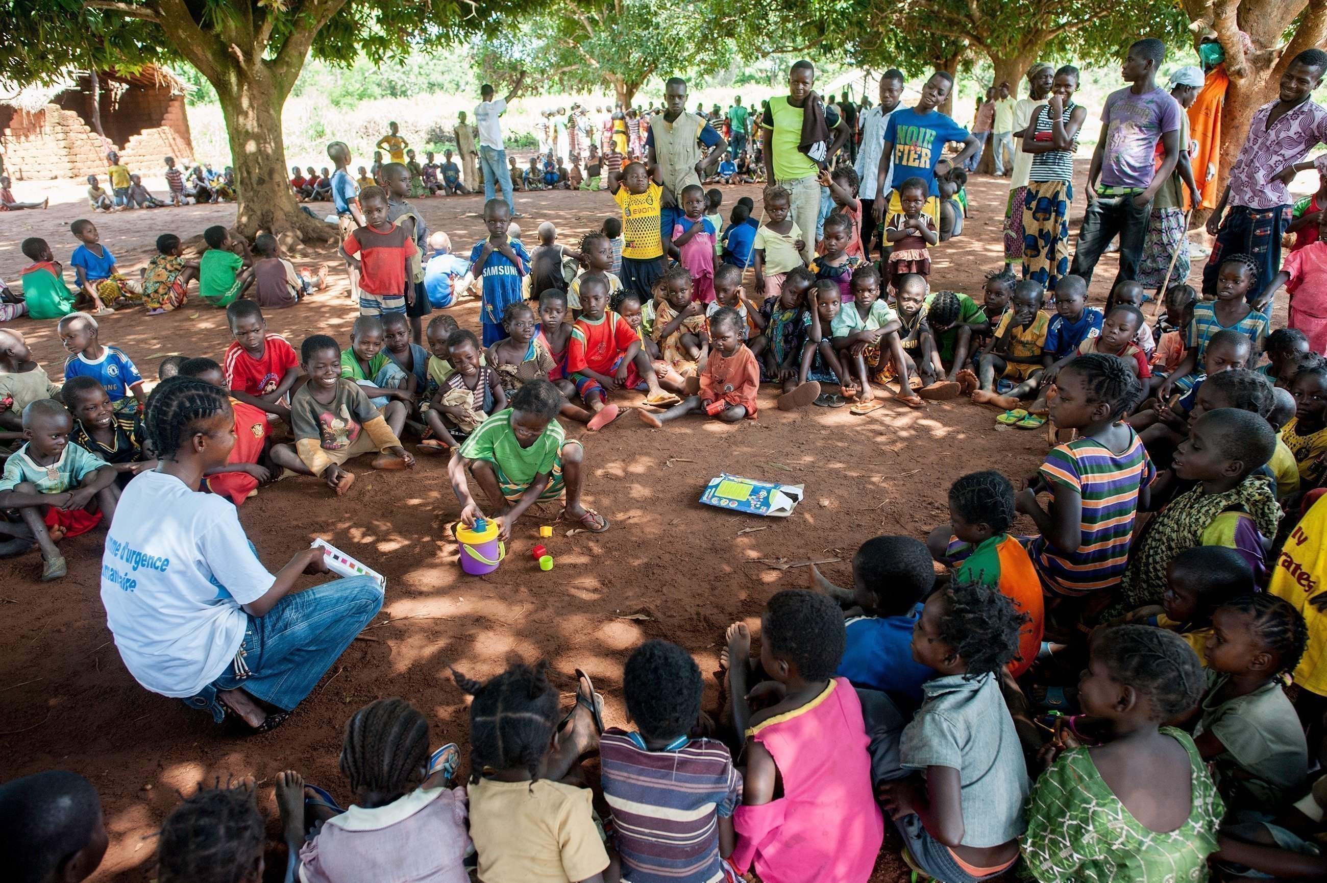 Viele Kinder sitzen mit einem SOS-Kinderdorf Mitarbeiter im Kreis und schauen einem Kind in der Mitte zu.